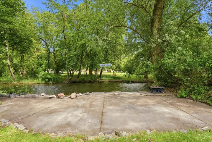 Waterfront property featuring mature trees and a concrete boat ramp