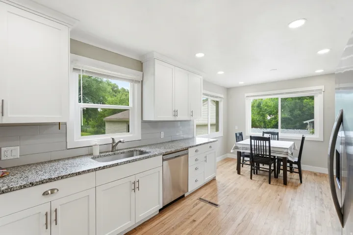Modern kitchen featuring white shaker cabinetry, stainless steel appliances, granite countertops, and a subway tile backsplash