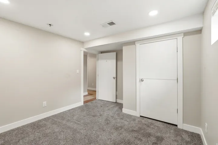 Neutral-toned room featuring plush grey carpeting and white baseboards