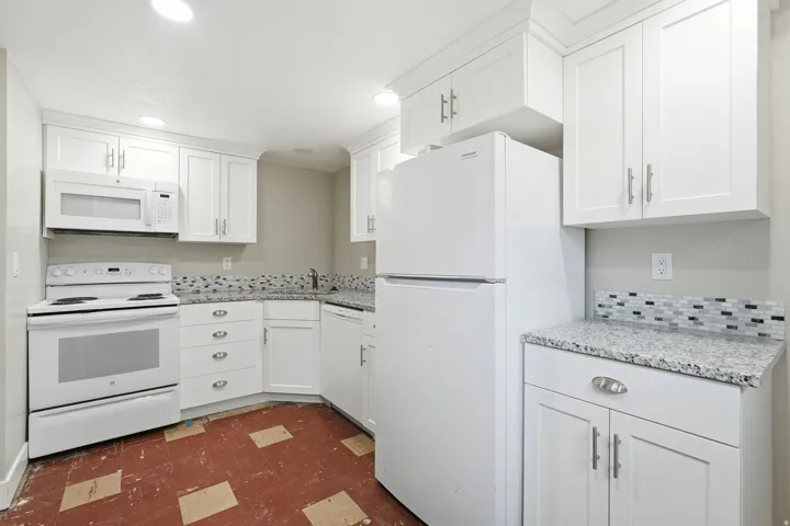 Kitchen featuring white shaker cabinetry, speckled countertops, a mosaic tile backsplash, and recessed lighting