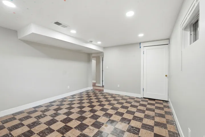 Spacious room featuring checkerboard tile flooring, recessed ceiling lighting, a white panel door, and a high-set window