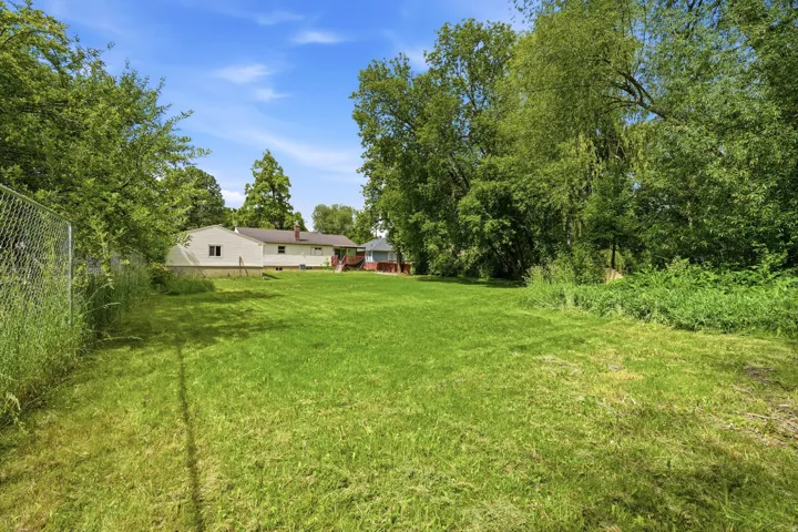 Expansive green lawn with mature trees bordering the property