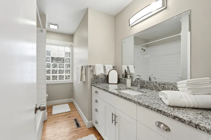 Well-appointed bathroom featuring a single vanity with a granite-style countertop, undermount sink, and chrome faucet