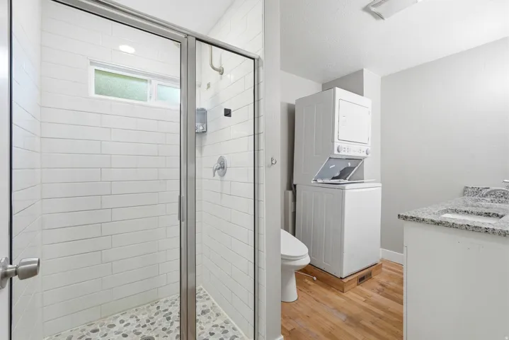 Shower with glass enclosure and pebble-tile flooring, complemented by white subway tile walls