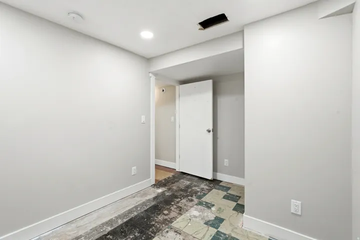 Room featuring light gray painted walls, white trim, recessed lighting, and an open doorway
