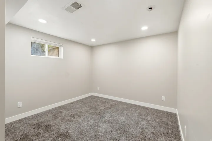Carpeted room featuring light gray walls, recessed lighting, and a white-framed window