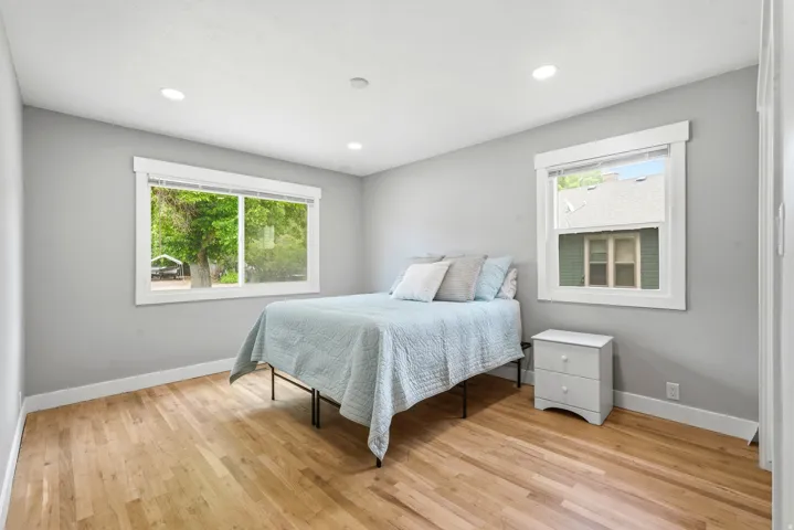 Bedroom featuring light wood-finish flooring, recessed lighting, and dual windows with white trim