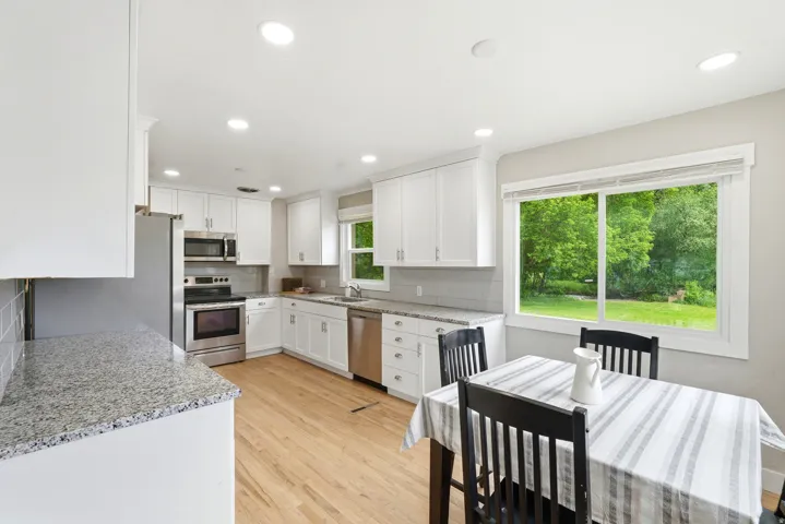 Open-concept kitchen featuring white cabinetry, light-toned wood-finish flooring, and recessed lighting