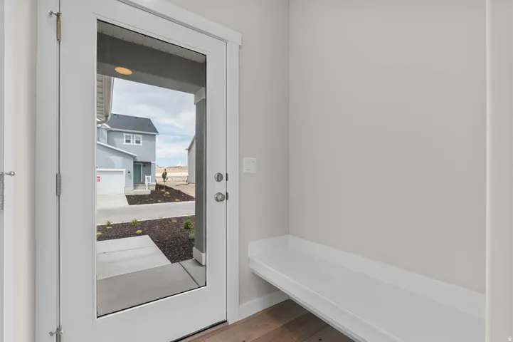 Entryway featuring a full-light door, integrated built-in bench, wood-finish flooring, and neutral wall tones