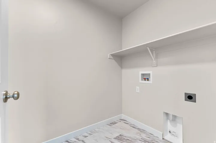 Utility area featuring a wall-mounted shelf, light neutral wall paint, and wood-finish flooring