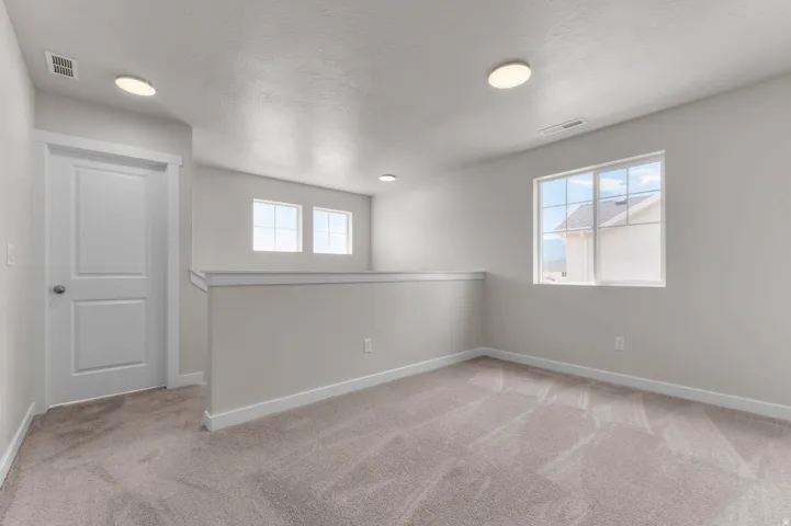 Open loft area featuring neutral-toned carpeting and light gray wall finishes