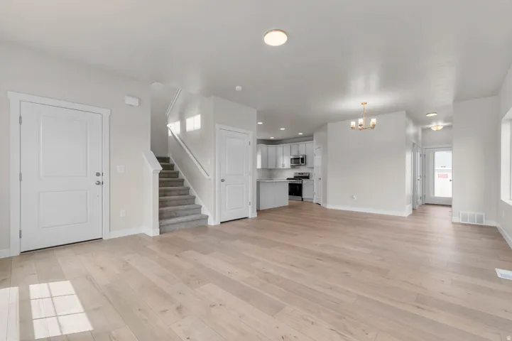 Expansive living area featuring light wood-finish flooring, recessed lighting, and a neutral color palette