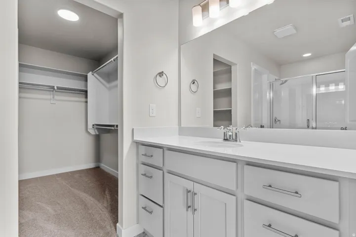 Bathroom vanity with white cabinetry and a white countertop, featuring a single undermount sink and a large mirror