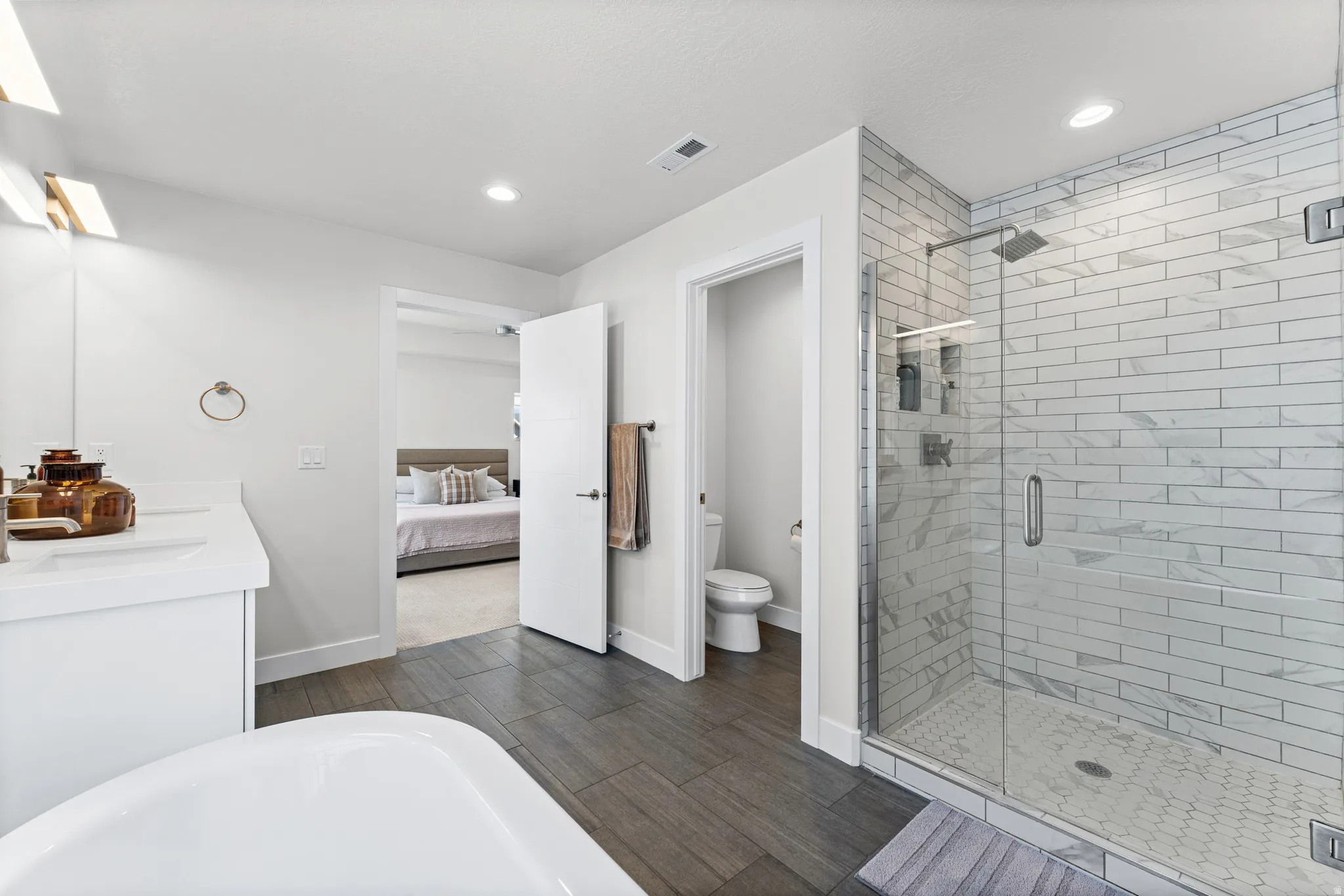 Walk-in shower with clear glass enclosure and white subway tile surround, featuring a rainfall showerhead