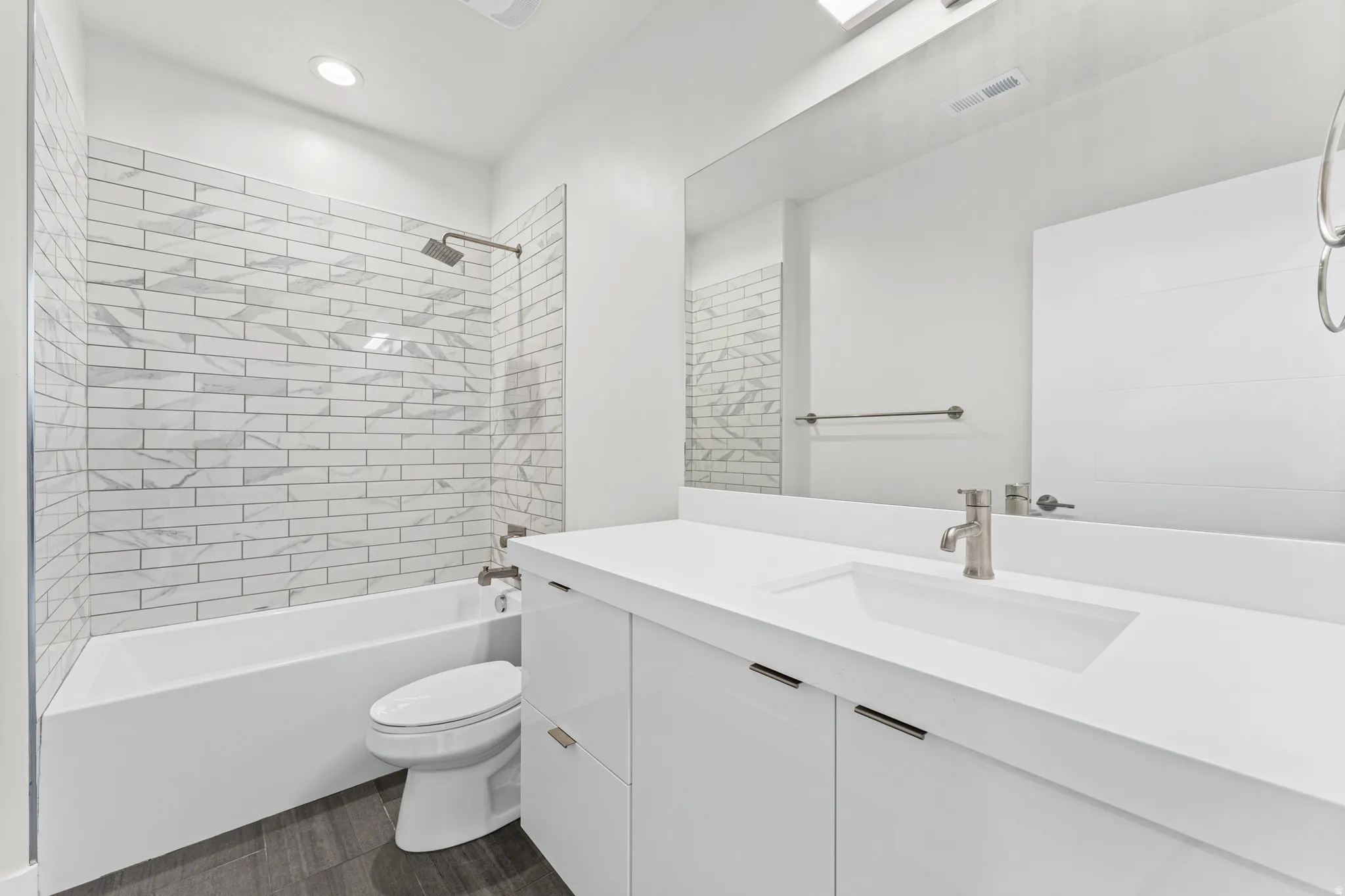 Modern bathroom featuring a vanity with an integrated sink, brushed nickel faucet, and full-width mirror