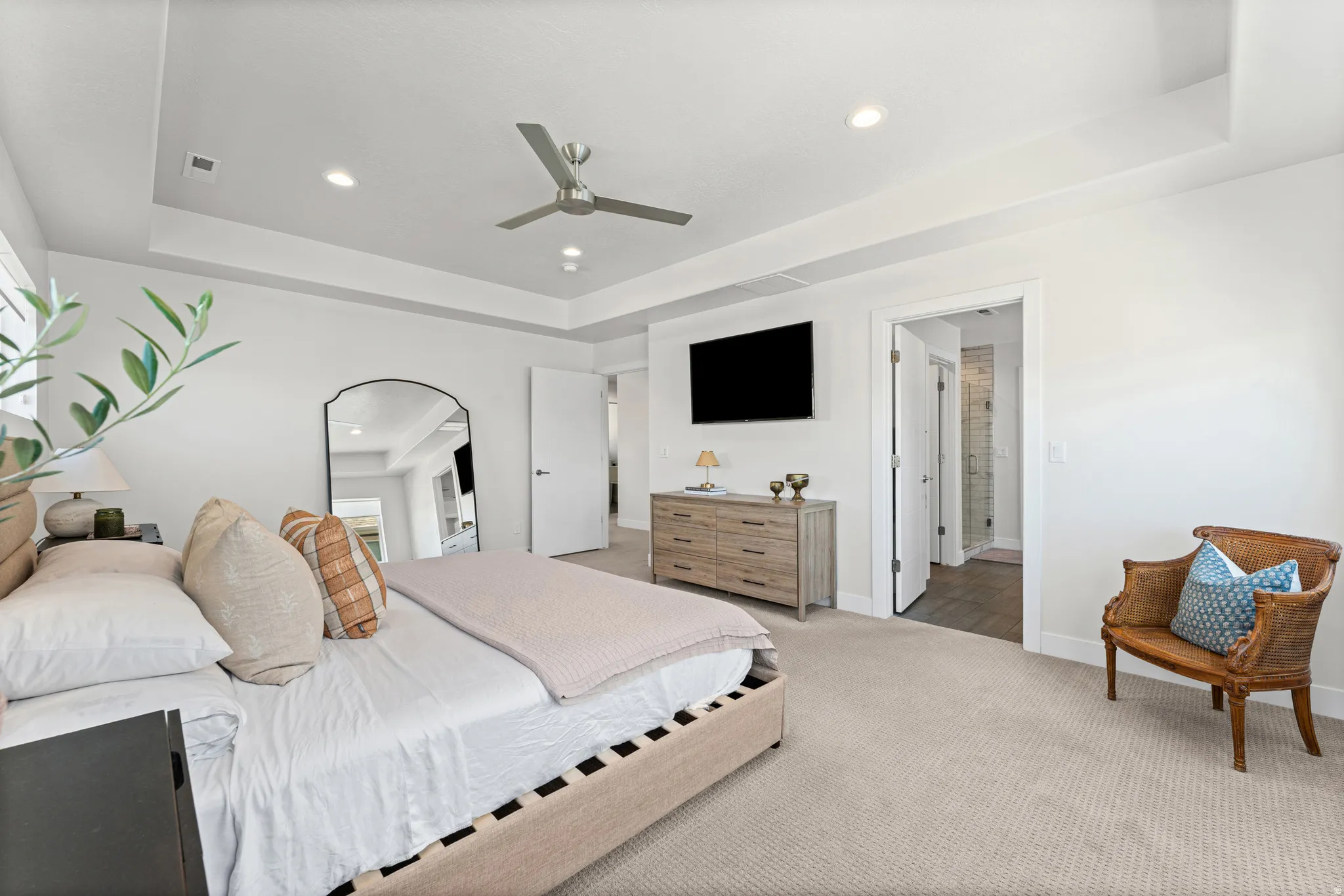 Bedroom featuring tray ceiling with recessed lighting, ceiling fan, and neutral carpet flooring