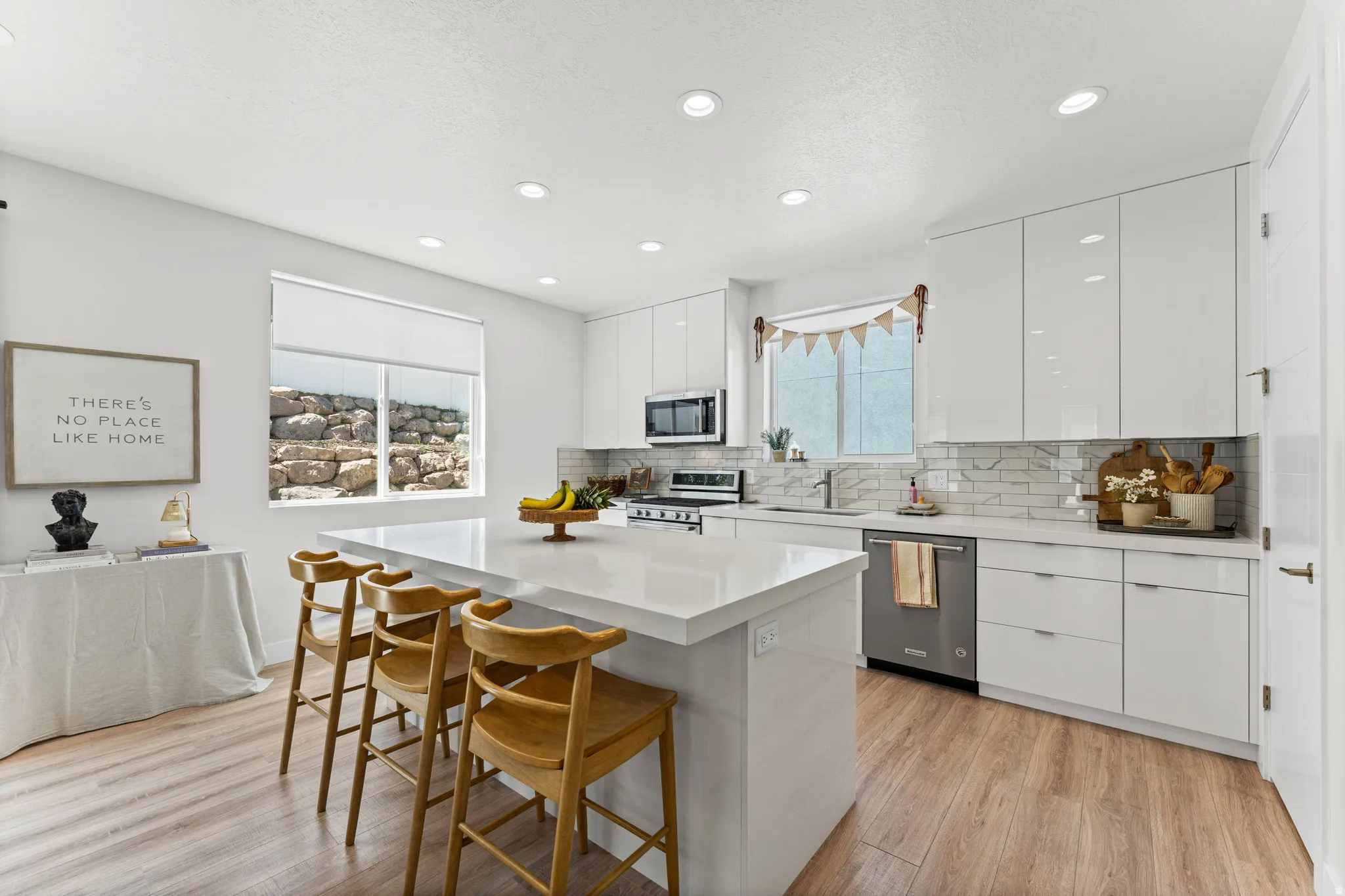 Contemporary kitchen featuring an expansive island with seating, glossy white cabinetry, and stainless steel appliances