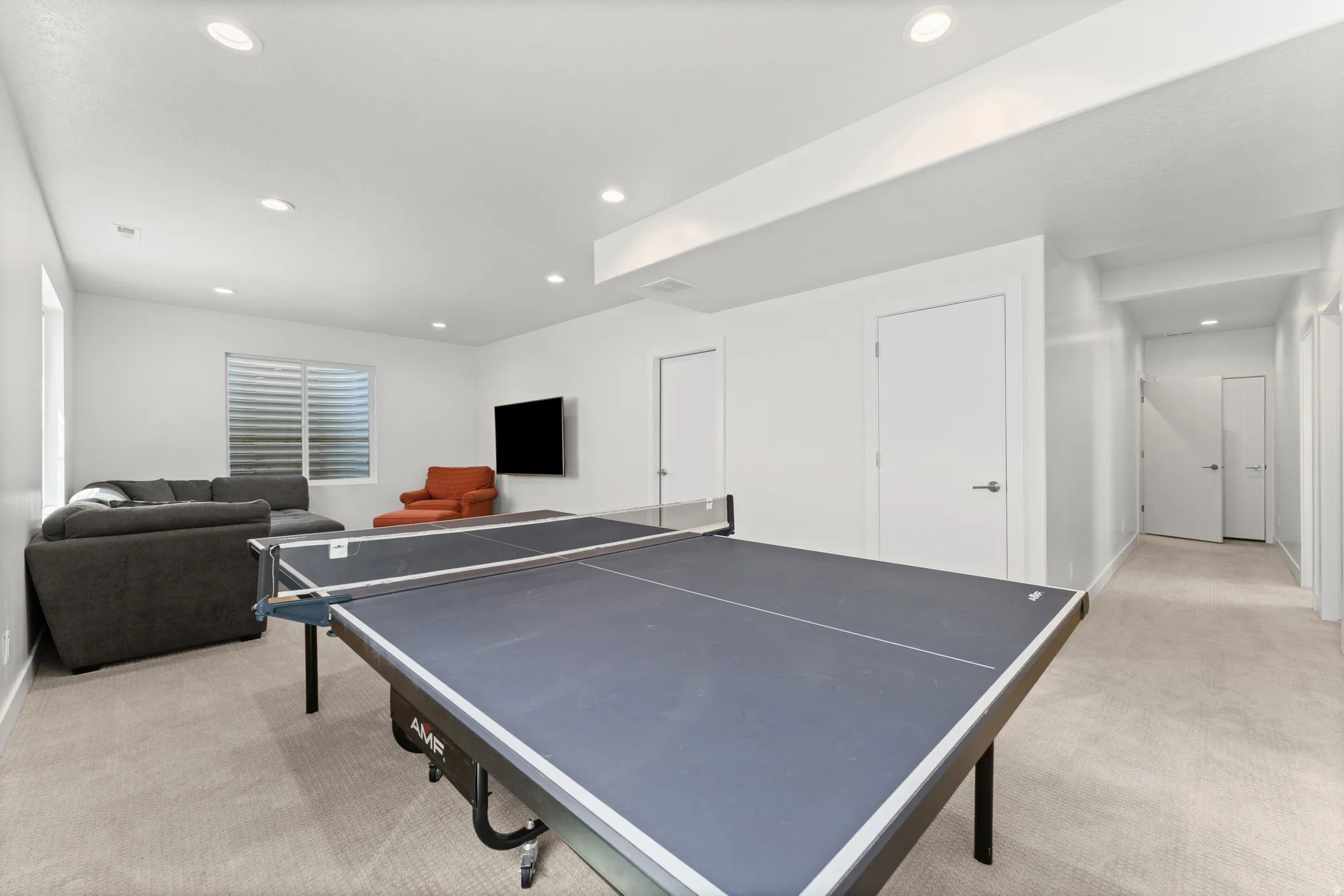 Versatile recreation area featuring recessed lighting, light-toned carpeting, and a window with horizontal blinds