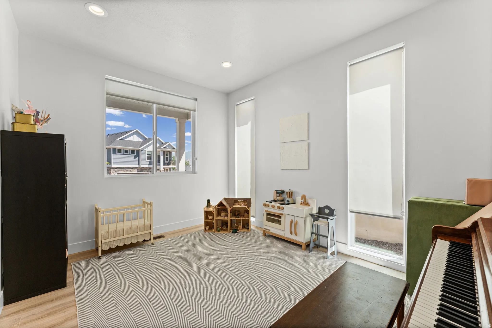Spacious room featuring light-toned walls, recessed lighting, and wood-finish flooring