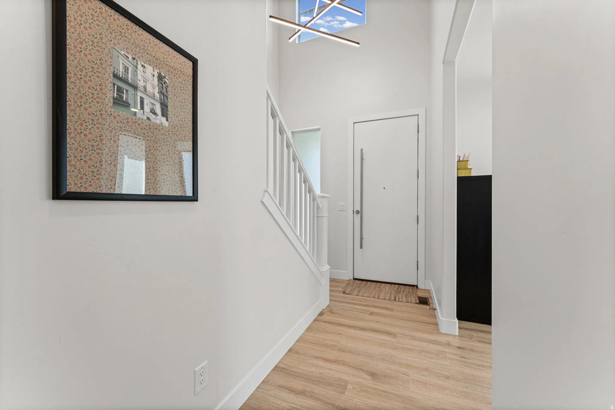 Two-story entryway featuring wood-finish flooring, white walls, and a contemporary light fixture