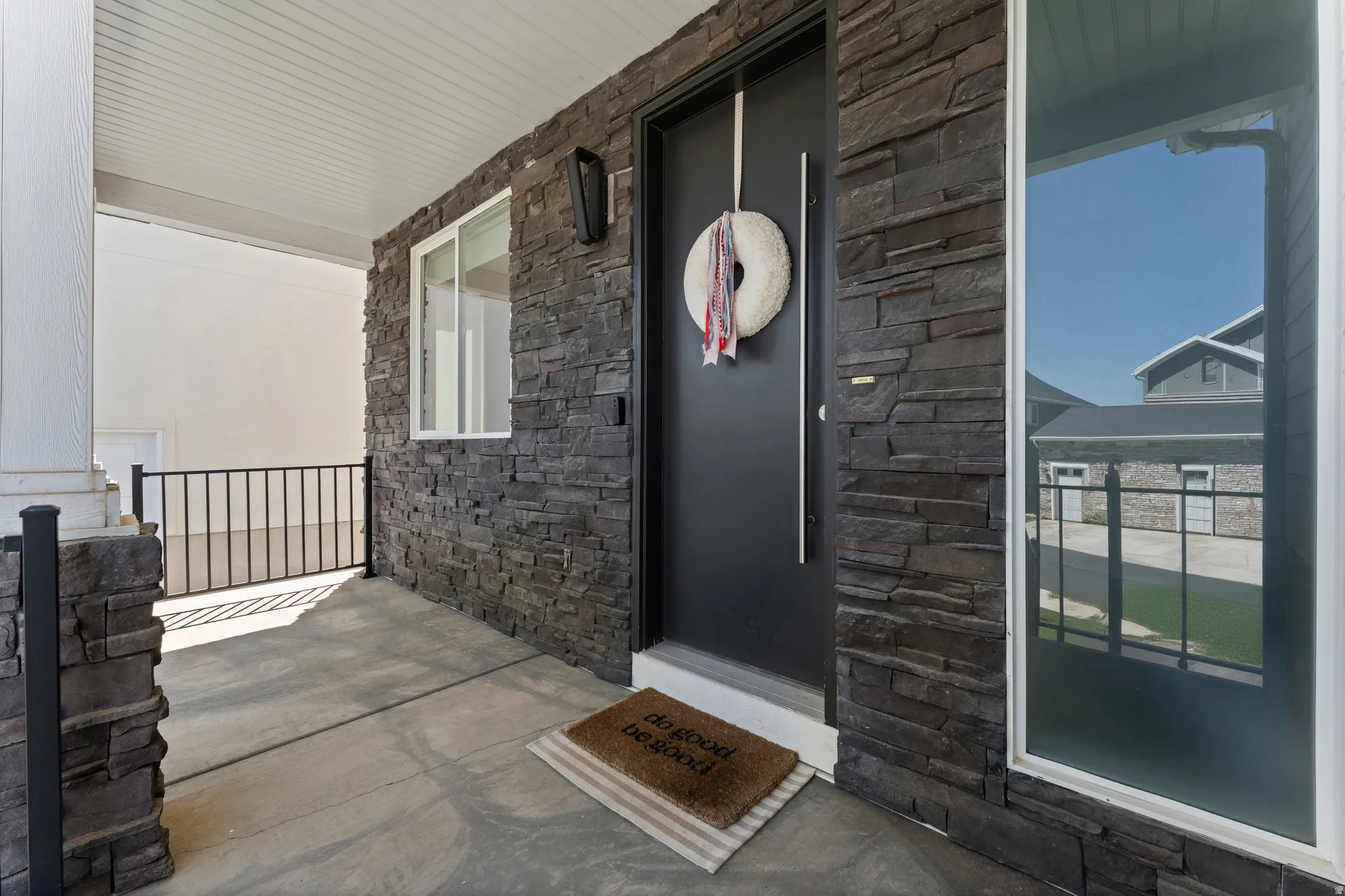 Covered front porch featuring a dark stacked stone facade