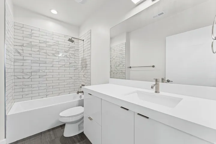 Modern bathroom featuring a vanity with an integrated sink, brushed nickel faucet, and full-width mirror