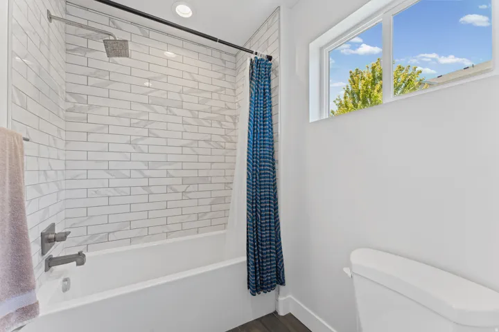 Bathroom featuring white subway tile shower surround with geometric accents, brushed nickel fixtures, a white soaking tub, and a window providing natural light