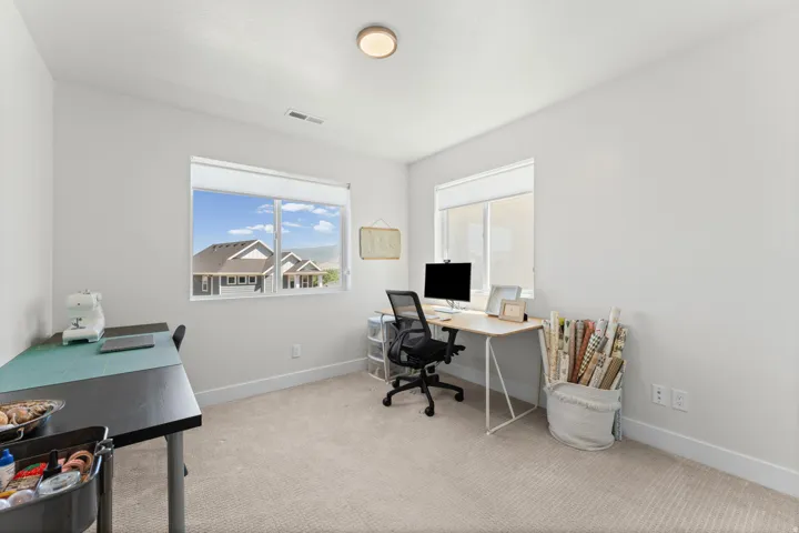 Spacious room featuring neutral carpeting, light-colored walls, and two large windows with white blinds