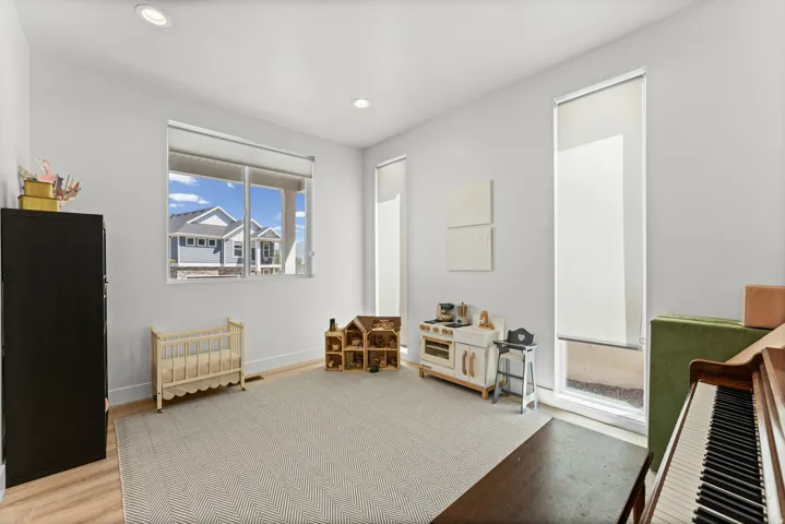Spacious room featuring light-toned walls, recessed lighting, and wood-finish flooring
