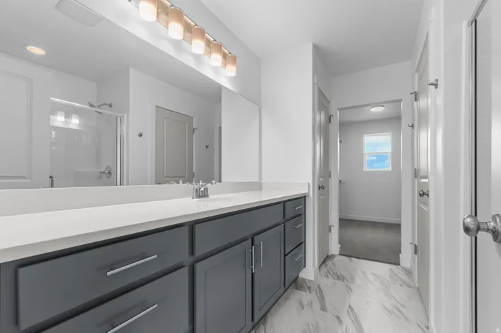 Bathroom featuring a dual vanity with a light-toned countertop, gray cabinetry, and a full-width mirror