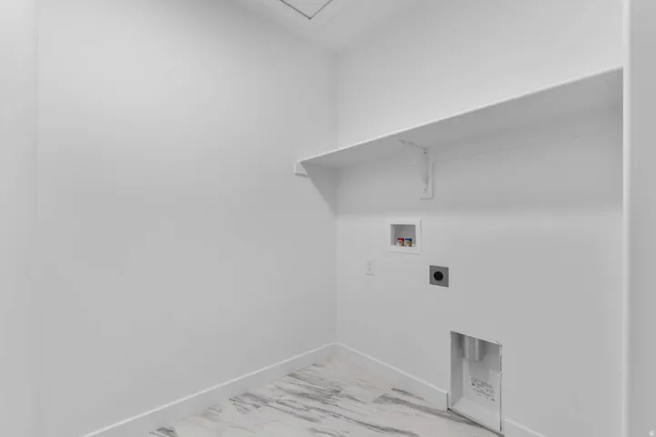 Dedicated utility space featuring a pre-installed shelf, white baseboards, and a light-toned, marble-patterned floor