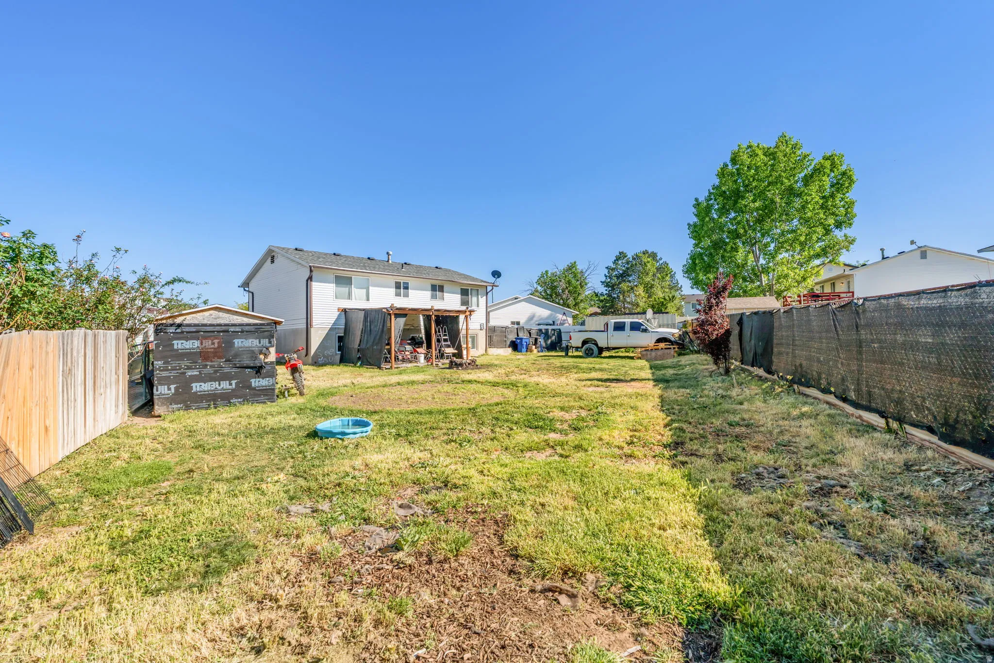 Expansive backyard featuring a partial wood fence and a partial chain-link fence with privacy screening