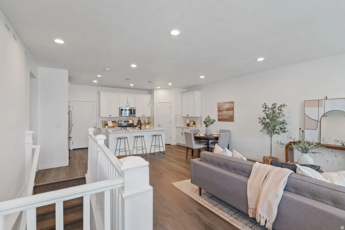 Open-concept living area featuring wood-finish flooring, recessed lighting, and a white baluster staircase