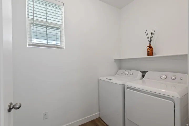 Dedicated laundry area featuring a window with blinds, a built-in shelf, and wood-finish flooring