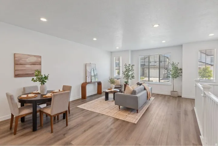 Open-concept living space with wood-finish flooring, recessed lighting, and white walls