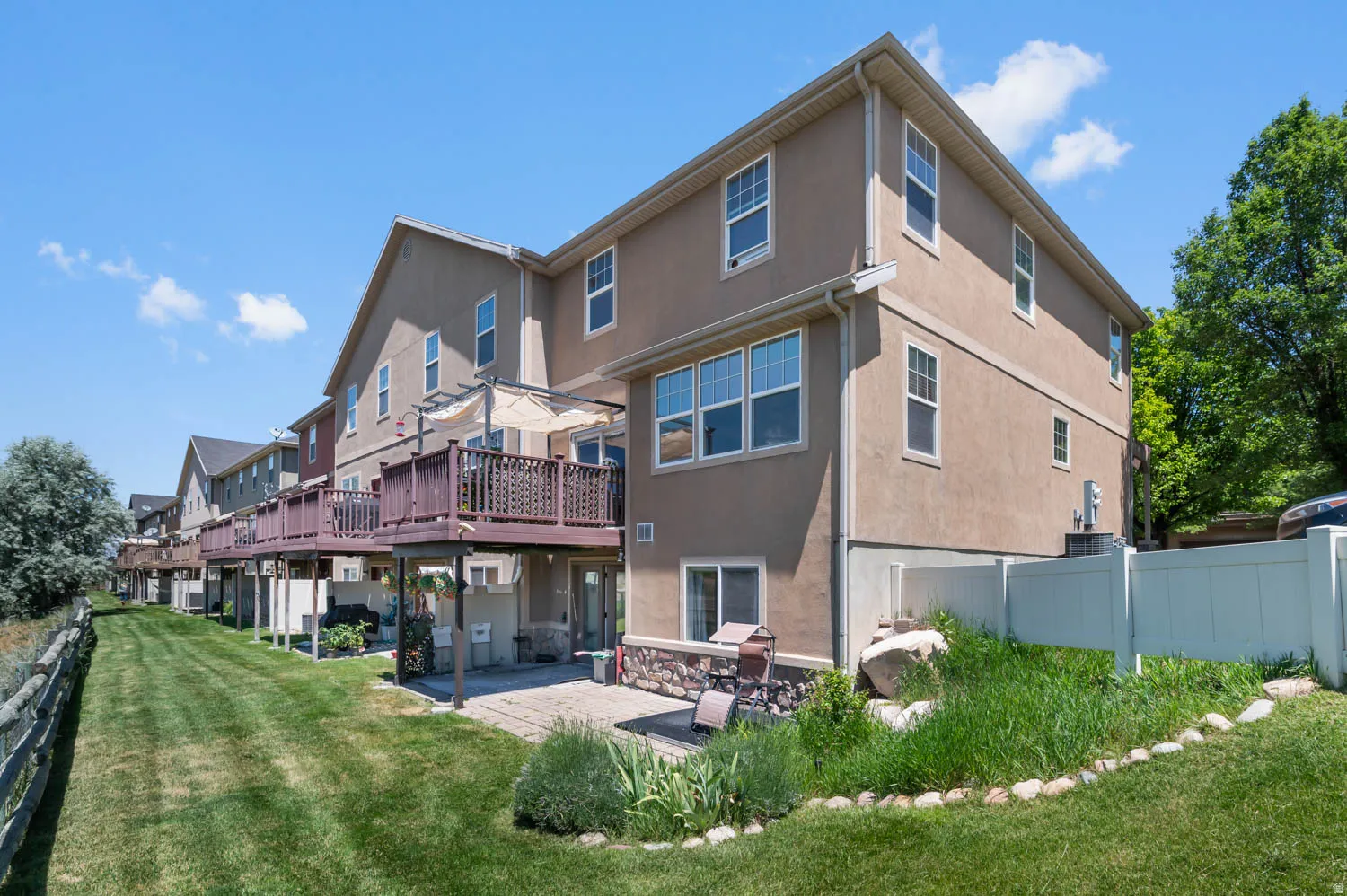 Rear exterior featuring a multi-level structure with an upper-level deck, lower-level patio, and a privacy fence
