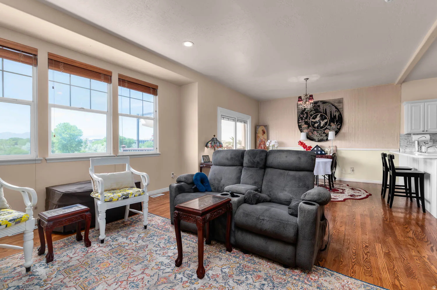 Open-concept living area featuring rich wood-finish flooring and a series of three large windows