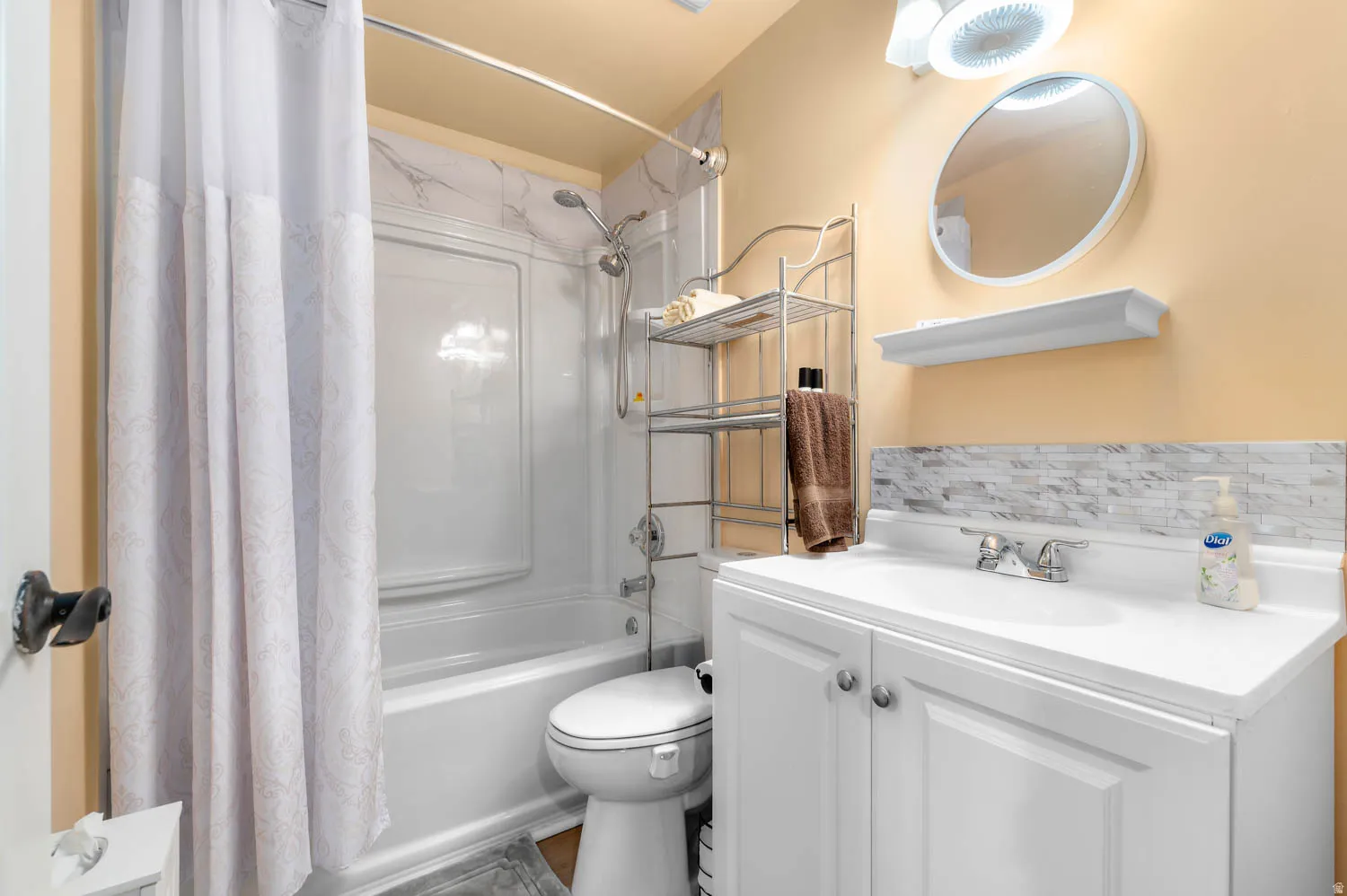 Bathroom featuring a white vanity with integrated sink, chrome faucet, and a tiled backsplash