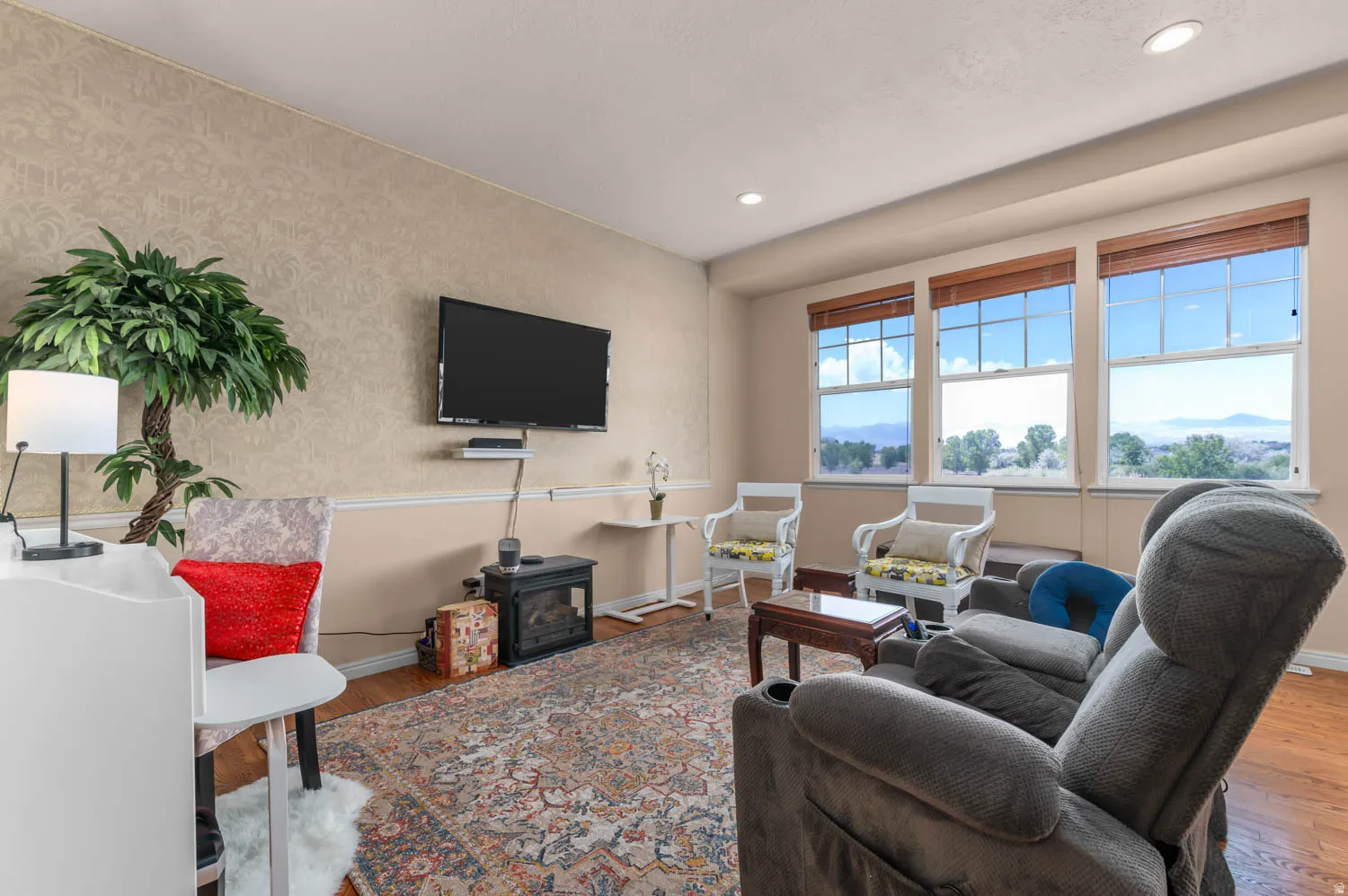Living area featuring wood-finish flooring, recessed lighting, and large windows with integrated blinds