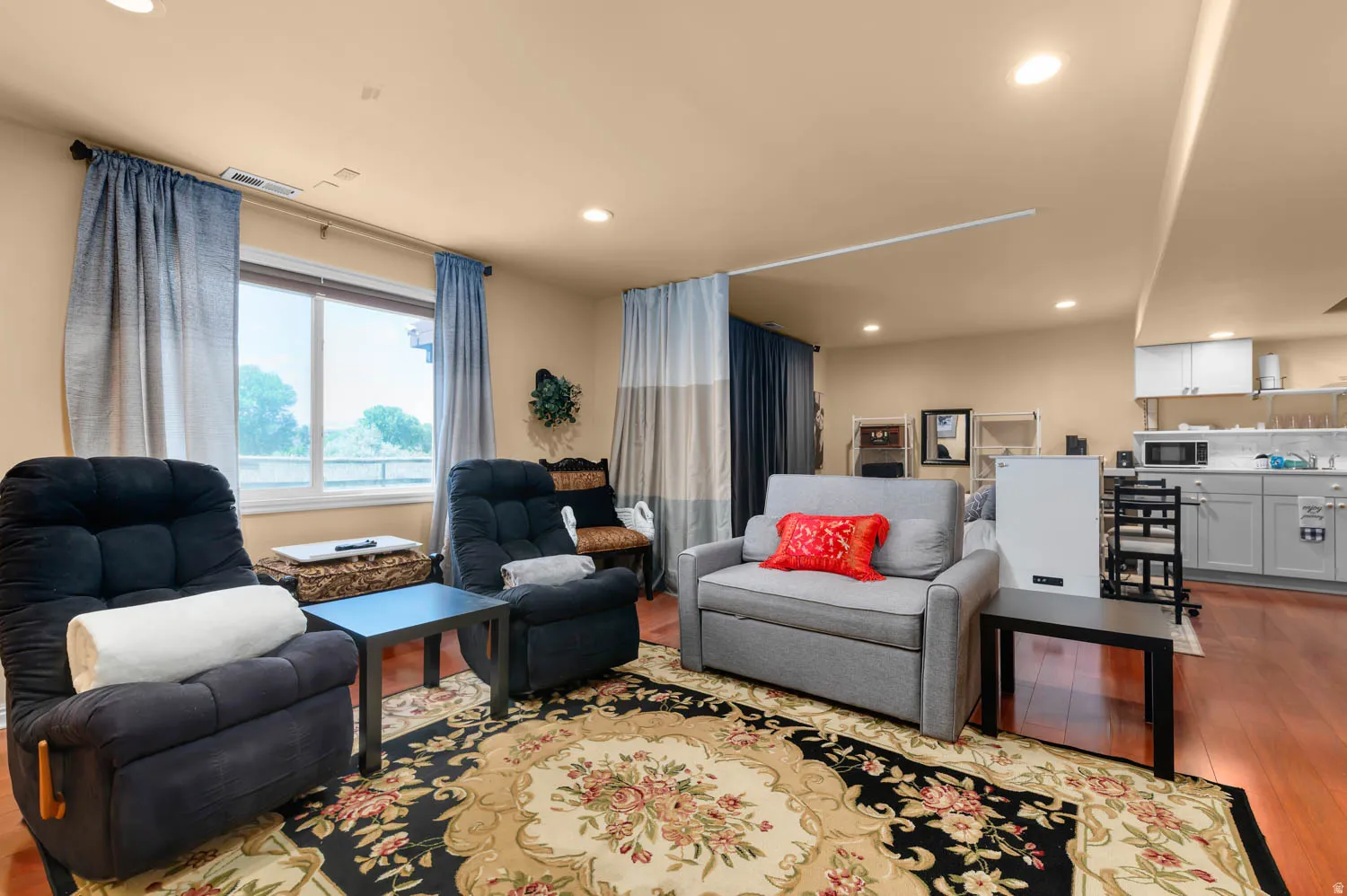 Open-concept living space with warm wood-finish flooring, recessed lighting, and a large window