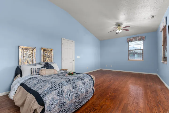 Spacious room featuring wood-finish flooring, vaulted ceiling, and ample natural light from multiple windows