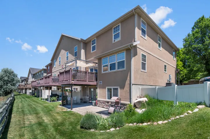Rear exterior featuring a multi-level structure with an upper-level deck, lower-level patio, and a privacy fence