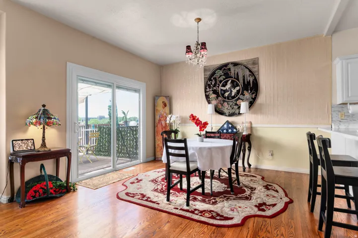 Dining area featuring wood-finish flooring, a contemporary chandelier, and direct access to an outdoor patio via sliding glass doors