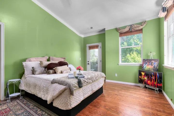 Spacious room featuring wood-finish flooring, a white trim crown molding, and a light green wall finish