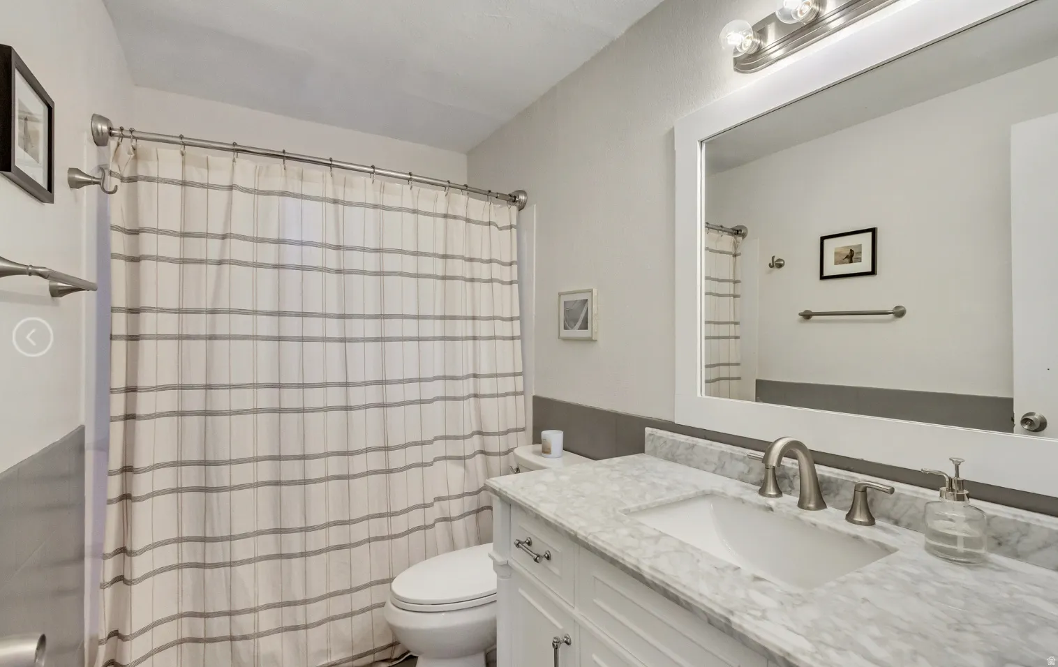 Bathroom featuring a white vanity with brushed nickel hardware, an integrated sink, and a stone-finish countertop