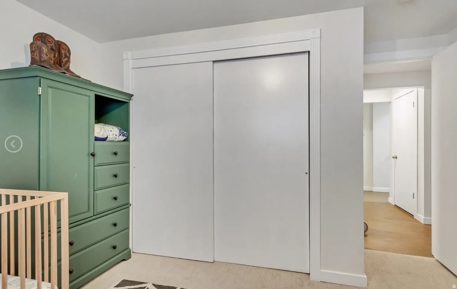 Interior closet with white sliding doors and white trim, featuring carpet flooring