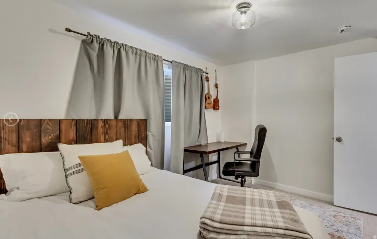 Bedroom featuring a wood-panel headboard, light gray window treatments, and a built-in ceiling light fixture