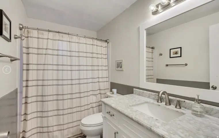 Bathroom featuring a white vanity with brushed nickel hardware, an integrated sink, and a stone-finish countertop