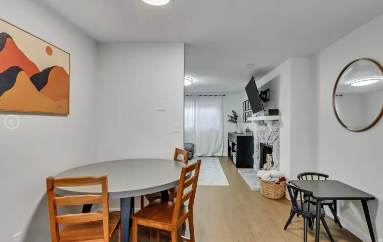 Open-concept living space featuring wood-finish flooring, recessed lighting, and a white stone-clad fireplace