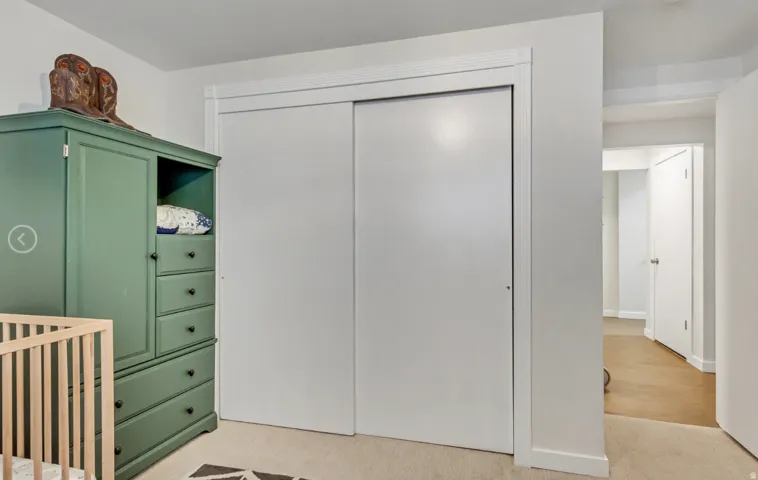Interior closet with white sliding doors and white trim, featuring carpet flooring